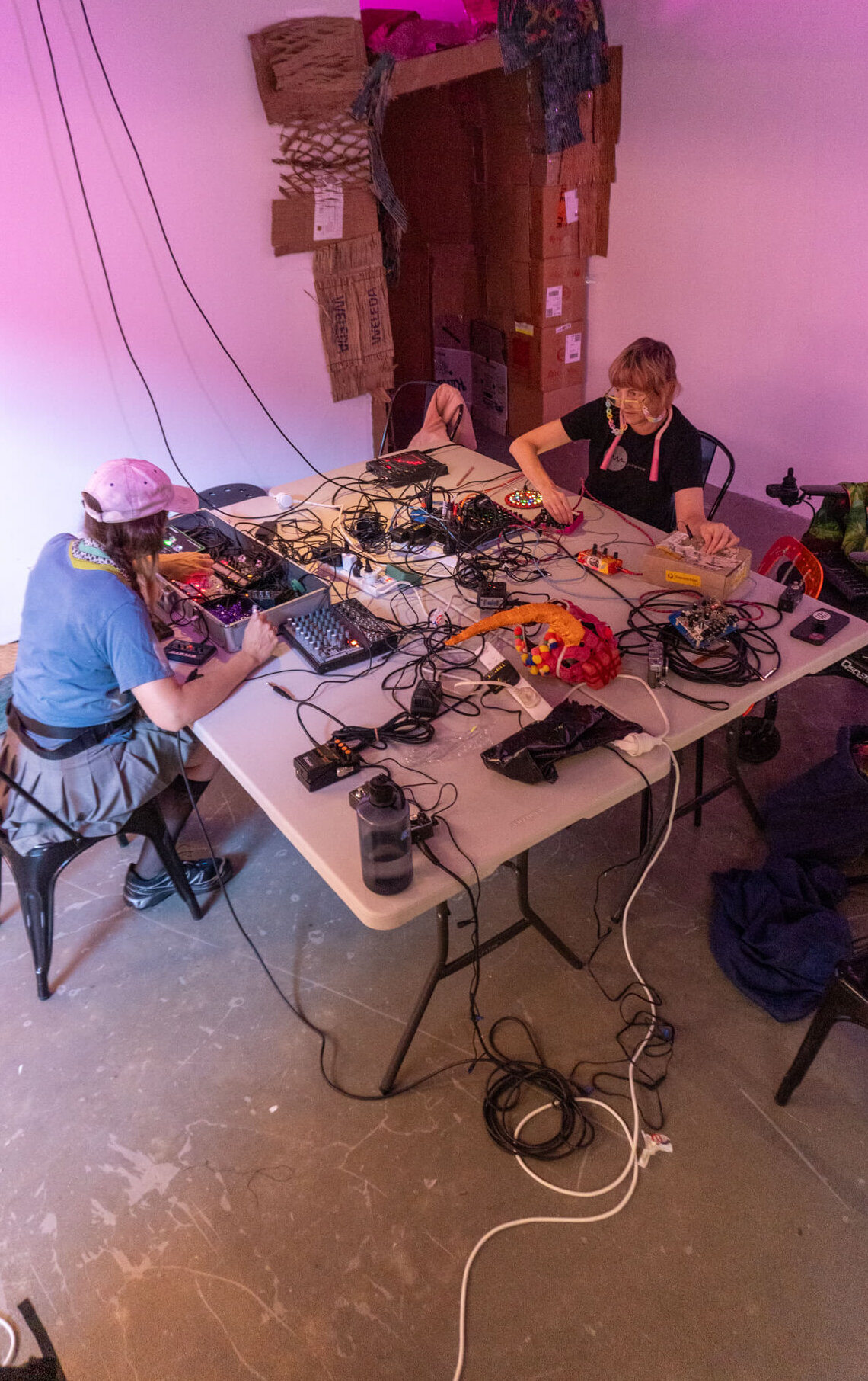 Alycia Bennett and Tara Pattenden at Metro Arts Gallery One, seated working together on synth electronics.